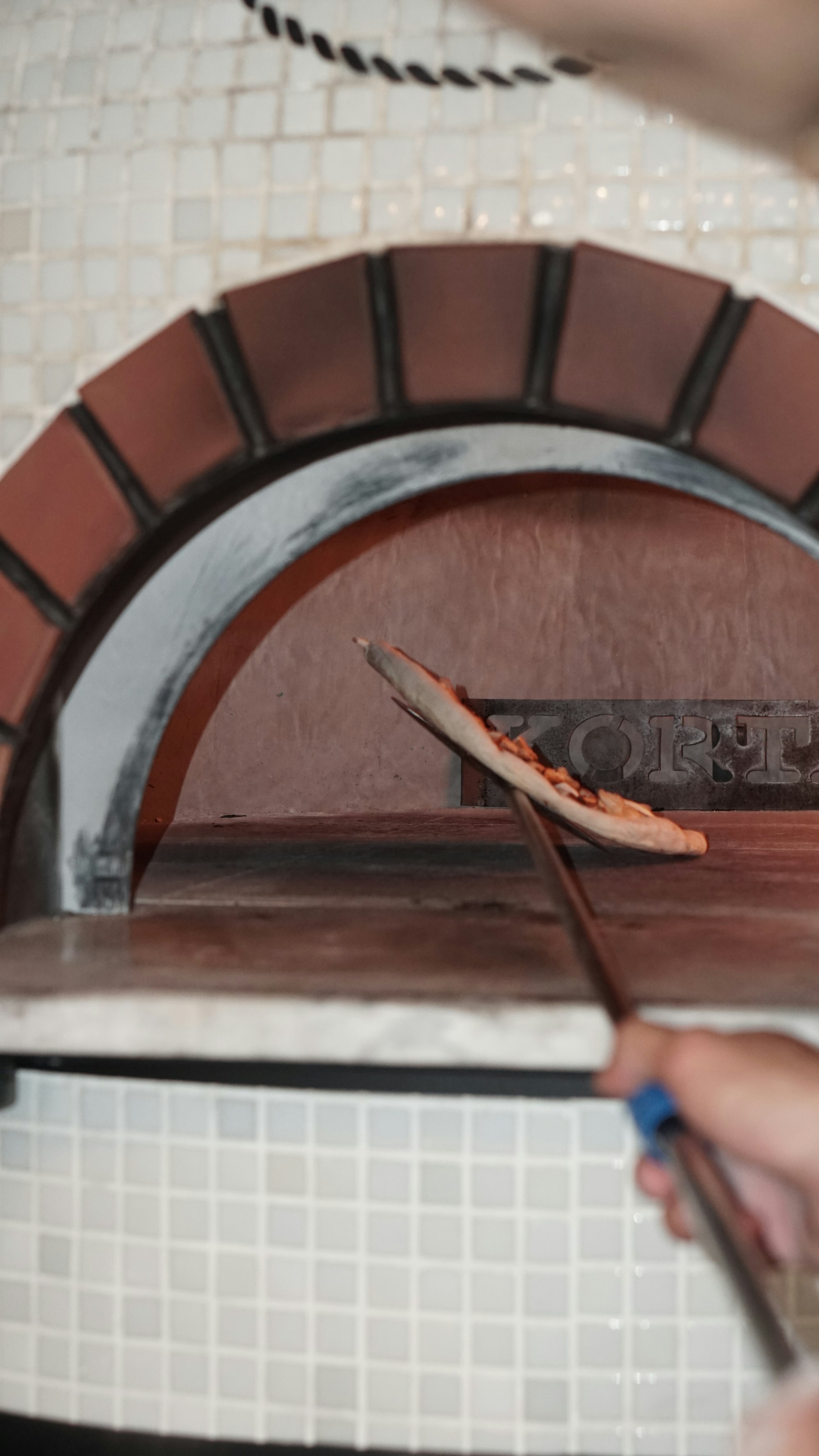 Pizza saliendo del horno en la pala